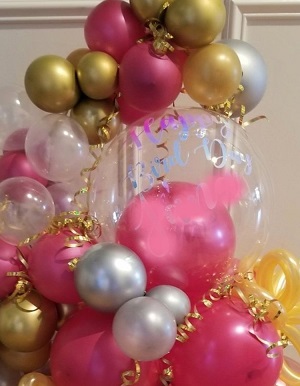 Clear Balloon encircled with gold pink silver balloons flowers and leaves gold ribbons