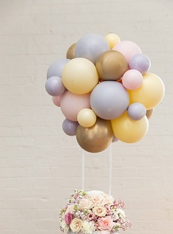 Pastel Balloon cluster on sticks with basket of pastel flowers at bottom