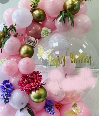 Clear happy birthday printed Balloon encircled with gold pink white balloons flowers and leaves