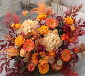 Orange roses gerberas carnations golden cane palm leaves tropical foliage in basket arrangement