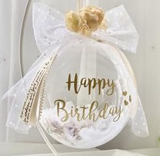 Happy birthday print on the transparent balloon white net wrapping and gold bow in a box